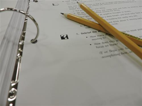 Two pencils crossed in a binder with paper 
